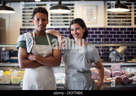 Proprietari di negozi di alimentari allegri in piedi di fronte al frigorifero Foto Stock