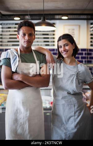 Proprietari di negozi di alimentari allegri in piedi di fronte al frigorifero Foto Stock
