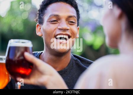 Allegro latino-americano che si diverte mentre beve birra con gli amici Foto Stock