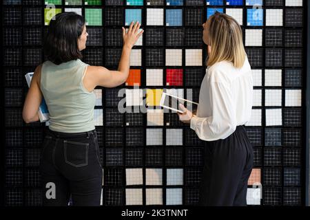 Due decoratori domestici femminili che scelgono i modelli nel loro studio Foto Stock
