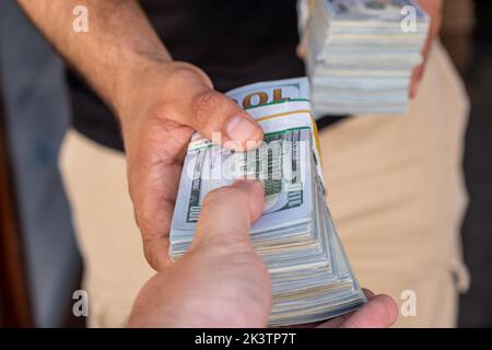 Pacchetti di dollari americani nelle mani di un uomo d’affari. Messa a fuoco selettiva Foto Stock