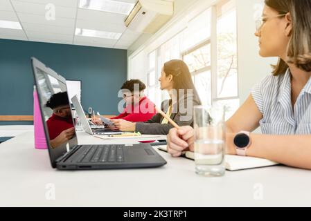 Compagnia di colleghi multietnici che si riuniscono in un moderno spazio di coworking e discutono insieme il progetto di startup in Costa Rica Foto Stock