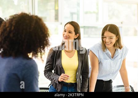 Contenuto colleghi ispanici in piedi al tavolo in moderno spazio di coworking in Costa Rica e condividere idee su nuova strategia di business Foto Stock