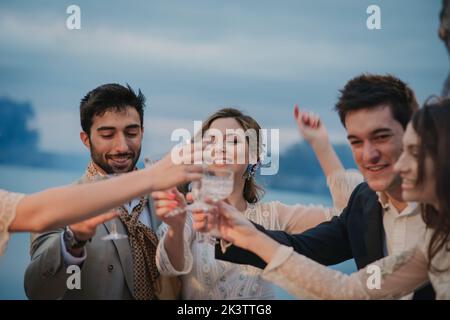 Giovani donne felici e uomini sorridenti che stringono bicchieri con bevande su sfondo sfocato Foto Stock