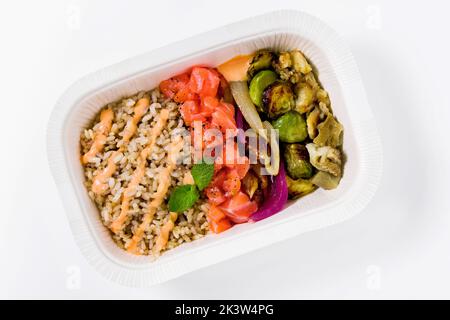 Insaporire con riso marrone, salmone e verdure alla griglia in un contenitore di plastica da asporto Foto Stock