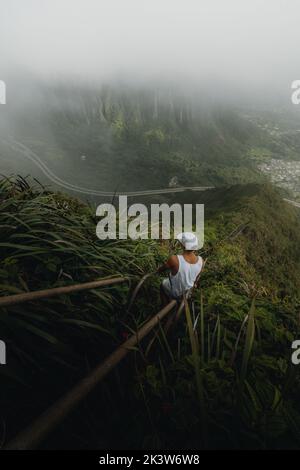 Uno scatto verticale di un uomo che si fa un'escursione sulle scale di Haiku a Oahu, Hawaii Foto Stock