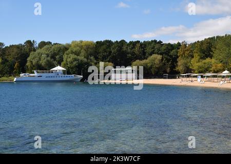 Resort sulla riva nord del lago Issyk-Kul. Spiaggia e nave bianca ormeggiata vicino alla costa. Kirghizistan Foto Stock