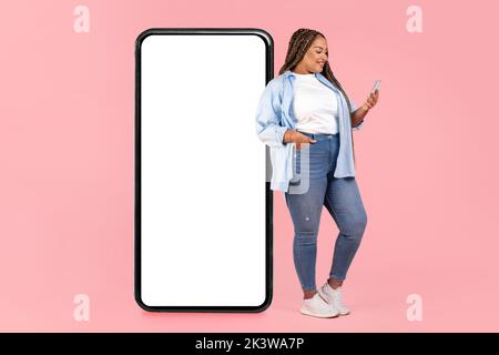 African Lady Pendente su Big Phone Texting su sfondo rosa Foto Stock