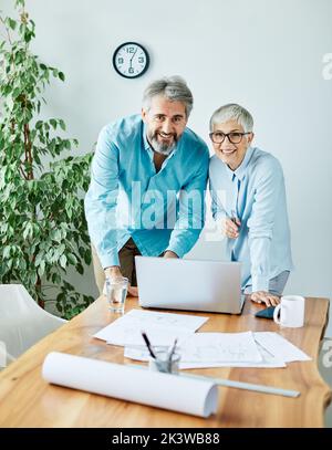 ritratto di due uomini d'affari senior che discutono su un notebook in ufficio Foto Stock