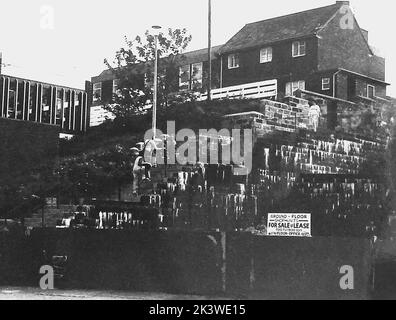 Una fotografia d'epoca di Bobby's Bank (nota anche come Bobbies Bank) prima di una nuova fase di sviluppo a Whitby, Yorkshire, Regno Unito. La banca originale utilizzata dai poliziotti è stata sostituita da passi, come si vede in questa foto. Quando si è svolto il processo di ristrutturazione, i negozi sono stati collocati sul sito e un'altra banca (quella attuale) con alcuni passi la ha sostituita. L'edificio moderno sulla sinistra è la biblioteca pubblica Whitby. Piazza della Stazione è appena fuori tiro sulla destra. Foto Stock