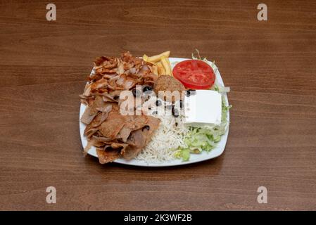 Piatto tipico misto di ristoranti pakistani in Europa con carne di agnello e pollo kebab, medaglione di falafel, olive nere con patatine fritte, riso bianco Foto Stock