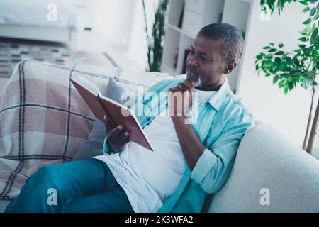 Foto di un uomo anziano seduto comodo divano letto interessante enciclopedia Think idea in soggiorno moderno Foto Stock