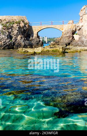 Palma, Maiorca, Spagna. Es Pujolar sulla spiaggia di Cala Major, un piccolo ponte verso una piccola isola vicino alla costa. Sullo sfondo la città di CAS Catala o S. Foto Stock