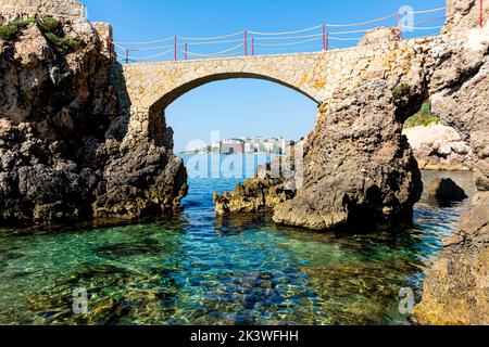 Es Pujolar sulla spiaggia di Cala Major, un piccolo ponte verso una piccola isola vicino alla costa. Sullo sfondo la città di CAS Catala o Ses Illetes Foto Stock