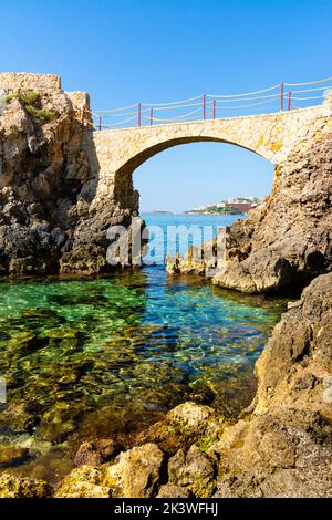 Es Pujolar sulla spiaggia di Cala Major, un piccolo ponte verso una piccola isola vicino alla costa. Sullo sfondo la città di CAS Catala o Ses Illetes Foto Stock