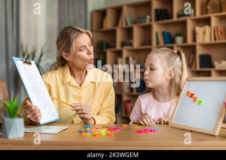 Formazione vocale per i bambini. Formazione specialistica femminile con la bambina intelligente, insegnando le sue esercitazioni di articolazione destra Foto Stock