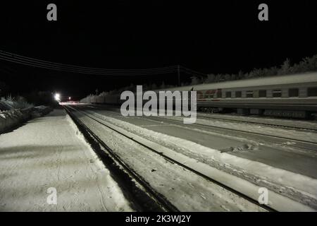 Vista sui binari ferroviari e sui vagoni ferroviari alla stazione Pyayve sul servizio ferroviario passeggeri più a nord del mondo tra Murmansk e Nikel nella notte polare Foto Stock