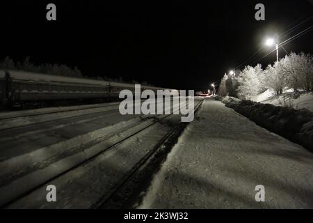 Vista sui binari ferroviari e sui vagoni ferroviari alla stazione Pyayve sul servizio ferroviario passeggeri più a nord del mondo tra Murmansk e Nikel nella notte polare Foto Stock