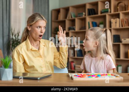 Professionista terapista di discorso femminile studiando insieme con la bambina del bambino, imparando esercitazioni di pronuncia di pratica Foto Stock