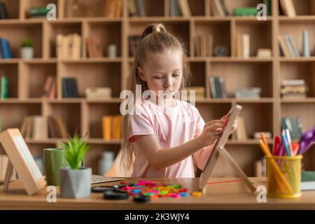 Graziosa bambina che si esercita con il bordo dell'alfabeto, facendo le parole dalle lettere colorful alla classe di sviluppo di preschool Foto Stock