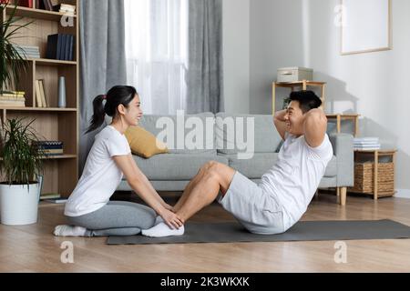 Vista laterale dell'uomo asiatico sportivo e della donna che si allenano insieme Foto Stock