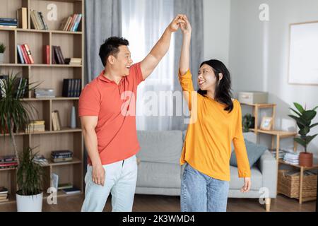 Coppia asiatica che ama godersi il tempo insieme a casa, ballare Foto Stock