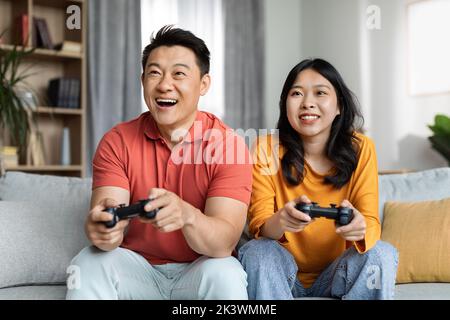Felice coppia coreana che gioca a videogiochi a casa Foto Stock