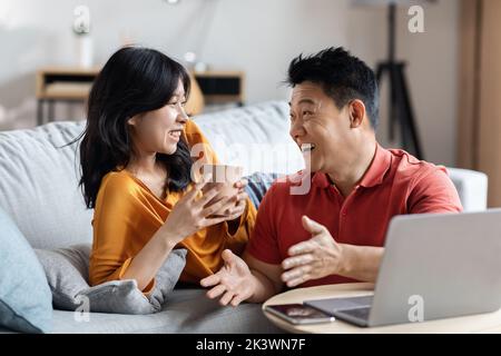 Allegra coppia coreana che pianifica una vacanza, utilizzando un computer portatile Foto Stock