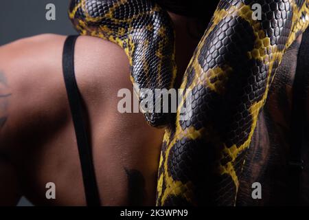 Foto ravvicinata dell'anaconda gialla sulle spalle della donna Foto Stock