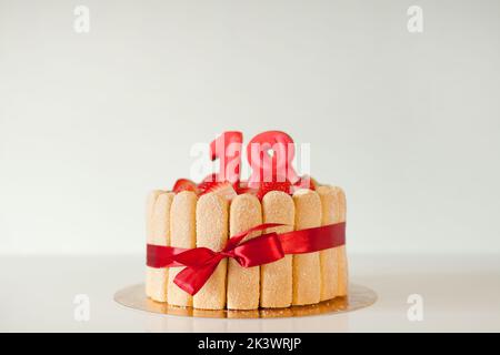 Torta deliziosa con numeri su sfondo grigio, spazio per il testo. Festa di arrivo - 18th compleanno. Foto Stock
