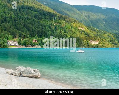 Stack di pietre sulla riva di acqua verde blu del lago di montagna Molveno. Villaggio e lago di Molveno ai piedi delle Dolomiti di Brenta. Foto Stock