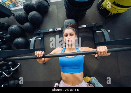 Donna che fa esercizi con il barbell su un banco di allenamento stampa Foto Stock