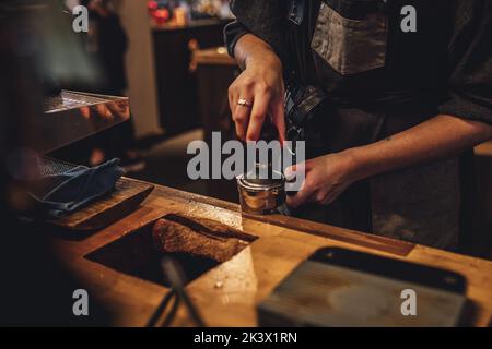 Un barista che macina i chicchi di caffè utilizzando un macinacaffè manuale catturato in una caffetteria Foto Stock