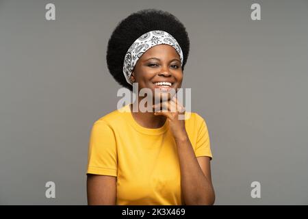 Donna afroamericana con fascia esegue schizzo mostrando emozioni positive in studio grigio Foto Stock