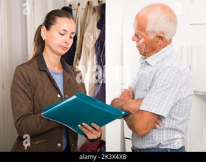 Il collettore femminile sta provando ad ottenere gli arretrati dall'uomo maturo alla porta domestica Foto Stock