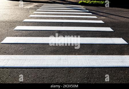 Attraversamento pedonale con linee bianche su asfalto. Attraversata la strada Foto Stock