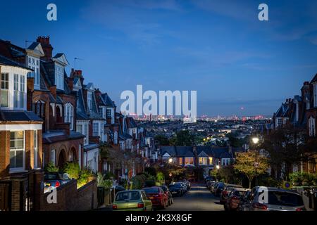 Una vista notturna su Londra che mostra case terrazzate e lo skyline di Londra verso la City. Questo illustra il mercato immobiliare con grande effetto creativo Foto Stock