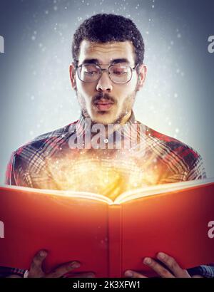 Oooooh, non ho visto quello che viene. Un'immagine ritagliata di un giovane adulto che legge un libro con pagine incandescenti. Foto Stock