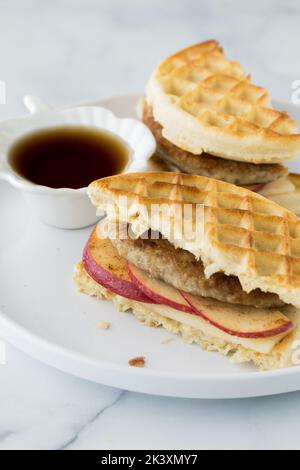 Un sandwich con waffle fatti in casa e salsiccia servito con sciroppo d'acero per l'immersione. Foto Stock