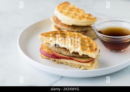 Un sandwich con waffle e salsiccia servito con sciroppo d'acero per l'immersione. Foto Stock