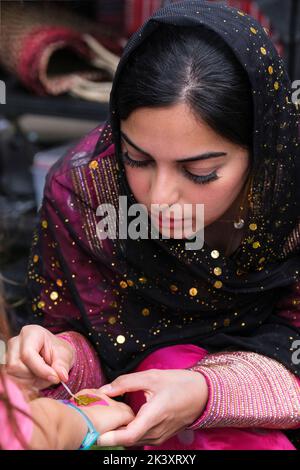 Giovane donna di Abu Dhabi applicare un Henna Design a un giovane ragazza 's polso in un tradizionale Folklife Festival. Foto Stock