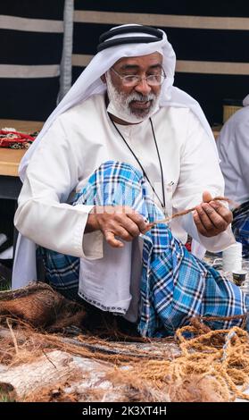 Afro-Arab da Abu Dhabi al Folklife Festival di Dishdasa, Ghutra, e AGAL, facendo corda di fibra di cocco per l'uso nella realizzazione di reti da pesca tradizionali. Foto Stock