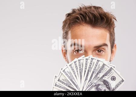 Ive ha ottenuto i soldi da risparmiare. Studio shot di un uomo d'affari che tiene un ventilatore di soldi davanti al suo volto. Foto Stock