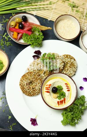 Ciotola di hummus fatta in casa, decorata con ceci bolliti, erbe aromatiche, pita e olio d'oliva su un fondo rustico di metallo Ciotola di hummus fatta in casa, decorata con ceci bolliti, erbe aromatiche, pita e olio d'oliva su un fondo rustico di metallo