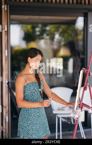 Giovane artista donna dipinge con una spatola sulla tela Foto Stock