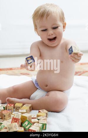 Mostrare interesse nei giochi educativi. Un bambino che gioca con i suoi blocchi di costruzione che osservano il soddisfare. Foto Stock