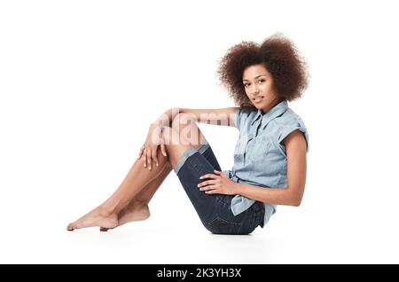 Per un'esperienza informale. Donna africana vestita casualmente seduta isolata su bianco. Foto Stock