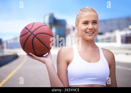 Gli shes hanno ottenuto il gioco. Vista ritagliata di un giocatore di basket femminile con un paesaggio urbano sullo sfondo. Foto Stock