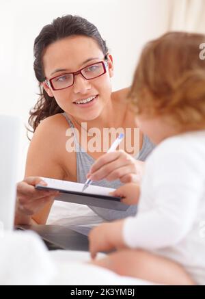 Tenerla occupata mentre cerca di lavorare. Una giovane madre che disegna un'immagine per la figlia del bambino. Foto Stock