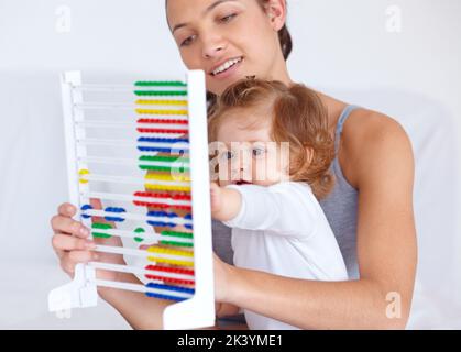 Imparare a casa. Una giovane madre che insegna alla bambina le basi della matematica usando un abaco. Foto Stock